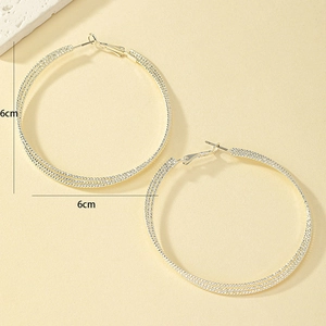 Macro shot of silver multi-layer twisted hoop earrings with 6cm diameter scale measurement