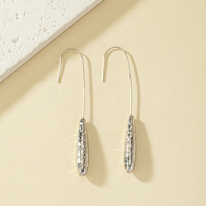 Macro detail of silver-finish water drop earrings with unique hammered metal texture