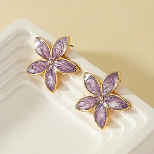 Elegant purple enamel flower earrings with gold metal trim on a white display stand