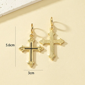 Vue macro de boucles d'oreilles croix dorées avec émail noir et dimensions 5,6 cm x 3 cm