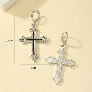 Détails macro des boucles d'oreilles croix en argent avec émail noir et métal brossé