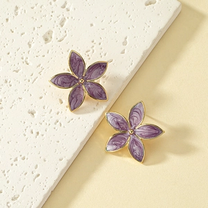 Elegant purple enamel flower stud earrings with gold trim on a natural stone base