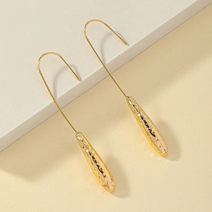 Detailed macro shot of gold long drop earrings featuring unique hammered metal texture