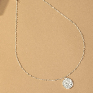 Close-up of vintage silver sun coin pendant on thin chain with detailed relief engraving