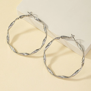Gros plan sur les boucles d'oreilles créoles torsadées argentées à texture spirale