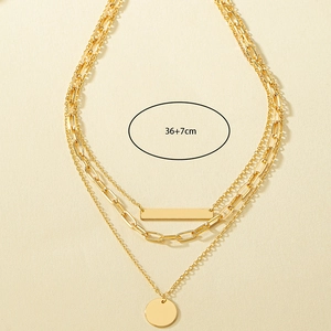 Detail of layered gold necklace showing rectangle bar and round coin pendants with 36+7cm length