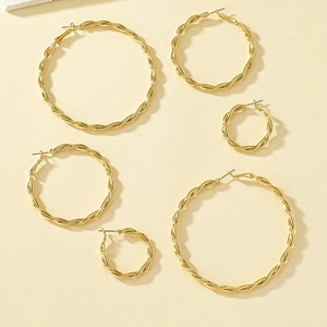 Detailed view of 3 pairs of gold-colored twisted hoop earrings in various sizes
