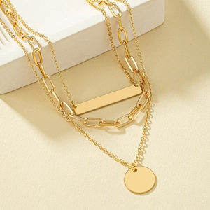 Layered gold necklace featuring flat round and rectangular pendants on mixed chain links