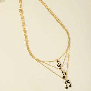 Three-layer gold chain necklace featuring black enamel musical note pendants and charms