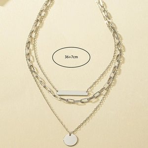 Close-up of a 3-layer silver necklace with rectangular bar and round disc pendants
