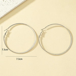 Detail view of 7.3cm oversized silver hoop earrings with subtle snake bone texture