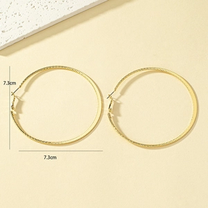Macro detail of large gold hoop earrings with textured surface and 7.3cm diameter