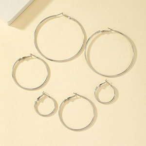 Detailed view of three pairs of polished silver hoop earrings in varying sizes