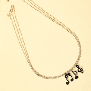 Macro detail of silver tone treble clef and musical note enamel pendant necklaces