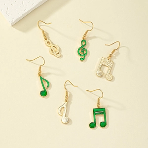 Dettaglio di orecchini a nota musicale placcati in oro con smalto verde su sfondo