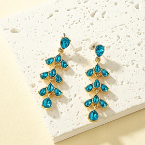 Detailed close-up of multi-layer gold leaf earrings with sea-blue teardrop crystals