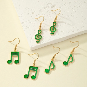 Dettaglio di tre paia di orecchini a nota musicale dorati con smalto verde su pietra