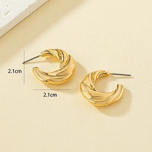Golden C-shaped twisted alloy earrings with 2.1cm diameter on a beige background