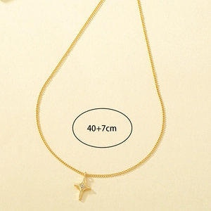 Gold minimalist cross star necklace with zircon stone on a beige textured background
