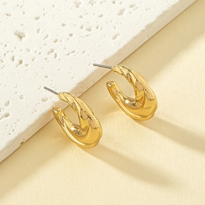 Minimalist twisted gold C-shaped hoop earrings with polished finish on a stone surface