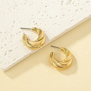 Minimalist twisted golden alloy C-shaped earrings with spiral texture on stone surface