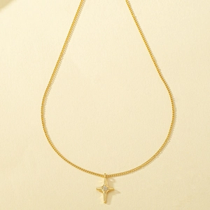 Elegant gold cross necklace with crystal star pendant on minimalist textured background