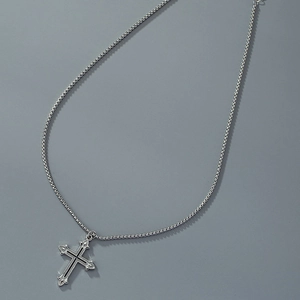 Close-up of gothic silver cross pendant with black enamel inlay on a steel box chain