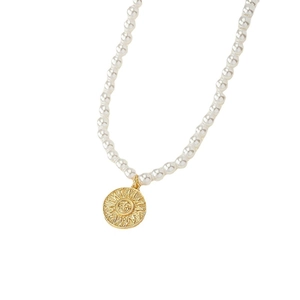 Collana di perle con ciondolo a moneta solare dorata vintage su sfondo bianco