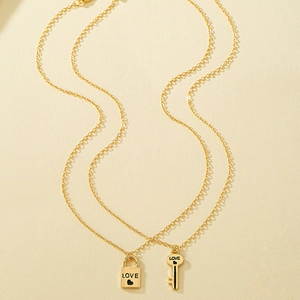 Detailed view of couple's gold lock and key necklaces with engraved LOVE and heart