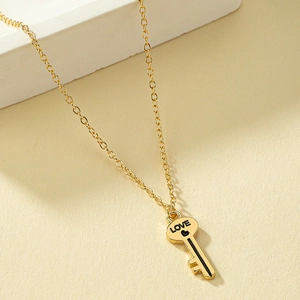 Golden key necklace with engraved LOVE heart pendant on a minimalist beige background