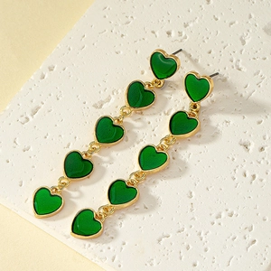 Long drop earrings with five green enamel hearts and gold chain on stone base