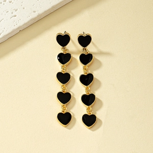 Close-up of dangling earrings featuring five black enamel hearts with gold metal links