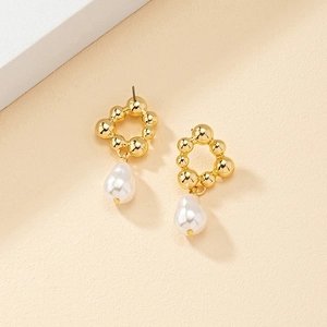 Boucles d'oreilles fleuries dorées avec perles baroques sur un fond épuré et chic