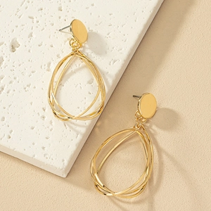 Elegant gold-tone tiered teardrop dangle earrings on a textured stone surface