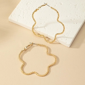 Détail de grandes boucles d'oreilles pétales dorées avec finition texturée sur pierre