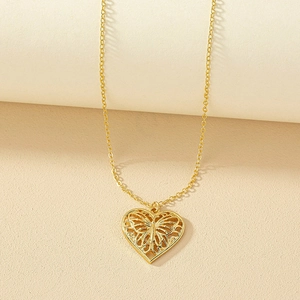 Collier avec pendentif coeur doré et papillon évidé sur un fond beige texturé élégant
