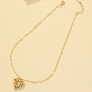 Collier élégant avec pendentif cœur doré et motif papillon sur fond beige texturé