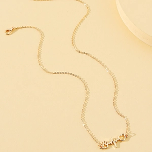 Minimalist gold heartbeat necklace with pet paw and heart pendant on a warm background