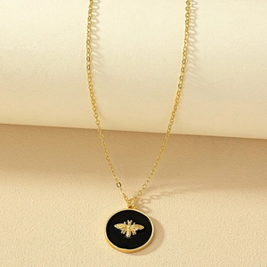 Golden chain necklace with black enamel bee pendant in a minimalist vintage style
