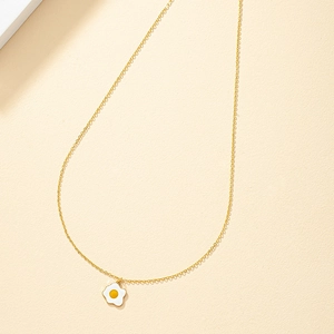 Minimalist gold chain necklace with a cute enamel fried egg pendant on beige texture