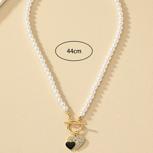 Pearls heart necklace with black enamel and zircon pendant on cream background 44cm