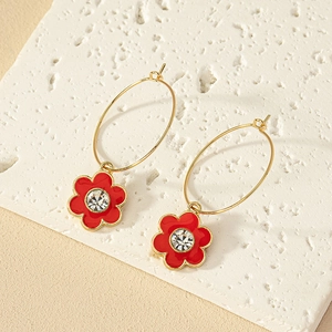 Details von roten Emaille-Blumenohrringen mit Zirkonia auf einer strukturierten Steinplatte