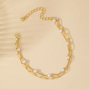 Détail du bracelet multicouche en chaîne dorée avec perles et fermoir réglable