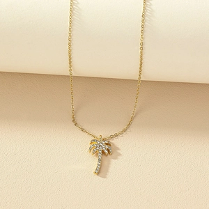 Luxurious gold palm tree necklace with sparkling rhinestones on a minimalist background