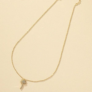 Luxury gold palm tree pendant necklace with sparkling white rhinestones on textured surface