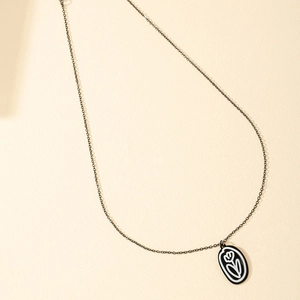 Collier à pendentif fleur en émail noir avec un design tulipe élégant sur fond papier beige