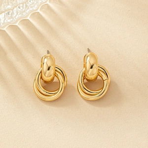Eleganti orecchini a cerchio geometrici placcati in oro su sfondo beige minimalista