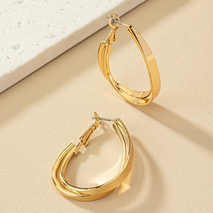 Gros plan sur des boucles d'oreilles goutte dorées multicouches aux lignes géométriques