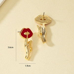 Dettaglio dimensioni orecchini a labbra in smalto rosso con gesto del dito dorato