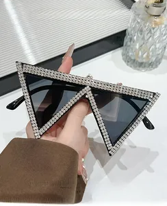 Dettaglio macro di occhiali da sole a triangolo con strass tenuti in mano, stile 2025